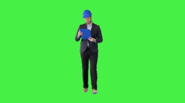 Konsantre iş adamı ya da bina sahibi yürüyen belgeleri okur Yeşil Ekran, Chroma Key 'de inşaat başlığı giyer.