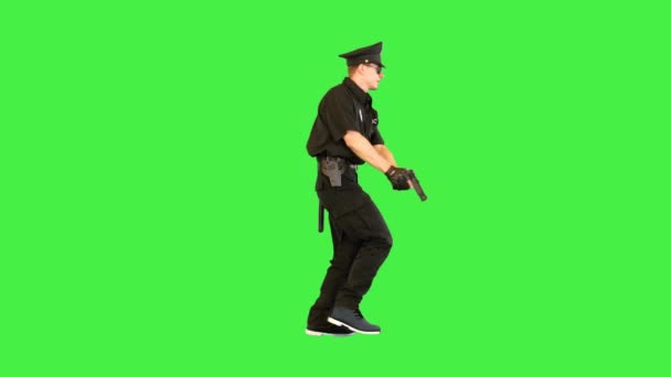 Polis i uniform kör siktar med en pistol på en grön skärm, Chroma Key. — Stockvideo