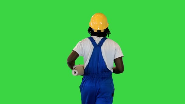 Handyman man in protective helmet hold wallpaper rolls walking and pointing with a brush to the sides on a Green Screen, Chroma Key. — Stock Video