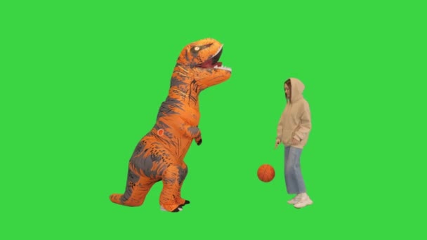 Mädchen beim Basketball mit einem Mann im Dino-Kostüm auf einem Green Screen, Chroma Key. — Stockvideo