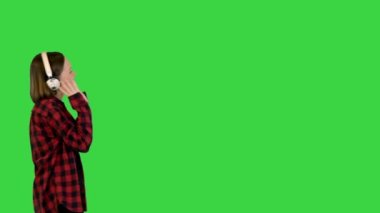 Genç kız yeşil ekranda kulaklıkla yürüyor, Chroma Key..