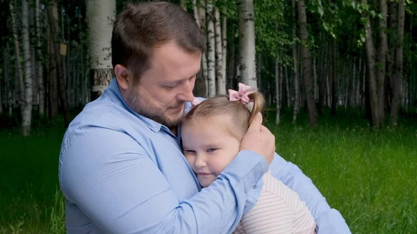 Padre forte tiene tra le braccia una dolce figlia, di 3 anni, la abbraccia e la abbraccia. Il concetto di genitorialità, superamento dei problemi nel rapporto tra padre e figlia, malattia, paura per — Foto Stock