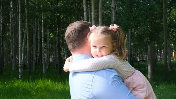 Buon padre che si porta al collo e abbraccia la figlia di 4-5 anni mentre cammina nel parco — Foto Stock