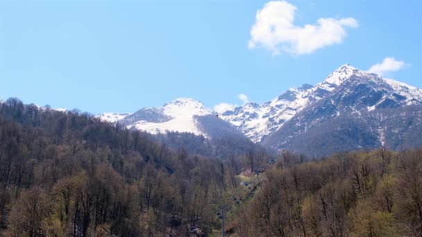 Picturesque landscape of snow-capped mountains with white clouds on a blue sky on a sunny day at Krasnaya Polyana in Sochi, Russia — Stock Video