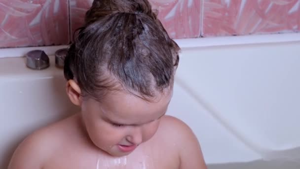 3 éves kislány otthon fürdik és mosakszik a fürdőszobában, a víz a gyermek szemébe kerül fürdés, sírás közben. Babaápolás, higiénia. — Stock videók