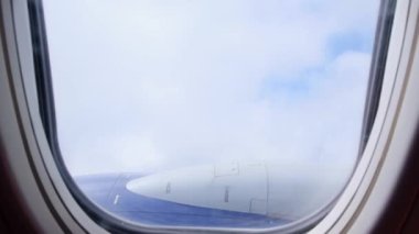 Bulutlar ve gökyüzü bir uçağın penceresinden görülebiliyor. Uçma ve seyahat kavramı, kanattaki uçak penceresinden görüş