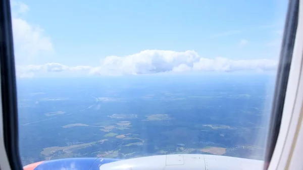 Wolken en lucht gezien door het raam van een vliegtuig. Concept vliegen en reizen, zicht vanuit vliegtuigraam op de vleugel — Stockfoto