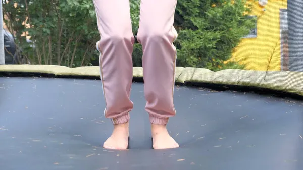 Une jeune femme saute sur une babut, un gros plan. Les jambes flottent dans les airs après avoir sauté sur un trampoline. Plaisir familial, divertissement et sport, orientation sélective — Photo