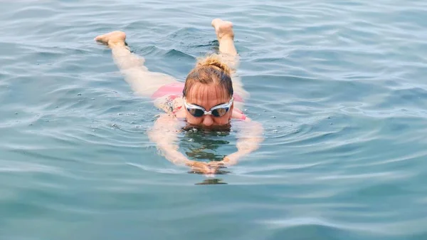 50-55-60 éves nő úszik a tengerben egy kúszás. Profi úszó, úszóverseny. Elöl úszik. Úszóórák. — Stock Fotó