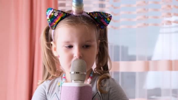 Amuzant fetiță de 4-5 ani, cu o jantă pe cap și un microfon în mâini, un copil cântă muzică karaoke, să se distreze la un eveniment viitor muzician voce tare solo — Videoclip de stoc