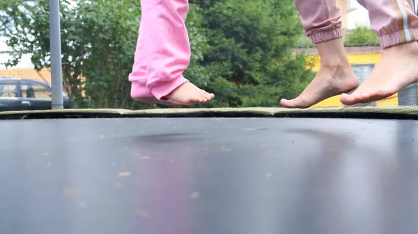 Young woman and a young girl are jumping on a ram, close-up. Legs float in the air after jumping on a trampoline. Family fun, entertainment and sports, selective focus — Stock Photo, Image