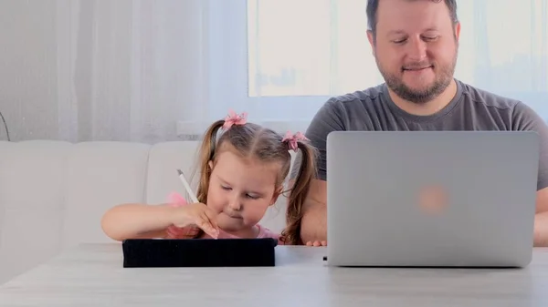 사업가의 아버지는 3 세된 어린 소녀 옆 집에서 태블릿으로 놀고 있다. 현대 가족. 프리랜서 개념. 제품에 대한 중독 — 스톡 사진
