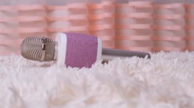Mikrofon beyaz kabarık bir battaniyenin üzerinde duruyor. Seyircilerin önünde gösteri yapma, karaoke yapma, eğlenme ve evde misafirlerle takılma konsepti. yıldız yeteneği gelişimi