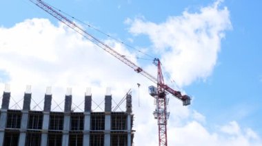 İnşaat vinci ve tamamlanmamış konut binaları mavi gökyüzü ve güneş ışığına karşı. Konut inşaatı, şehirdeki apartman binası, ipotek