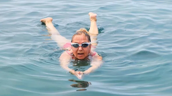 眼鏡と赤い水着の女性が海でクロール水泳を練習しています。プロの水泳、水泳レース。フロントクロールスイマー。水泳のレッスン. — ストック写真