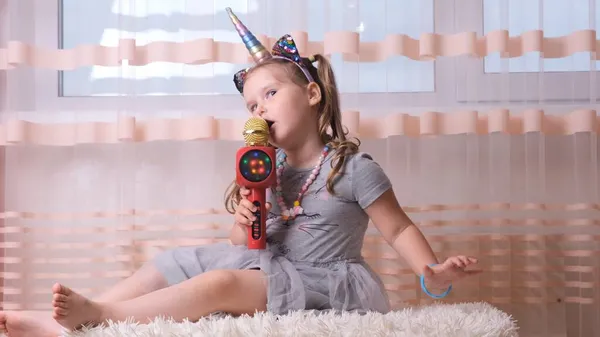 Vicces vonzó őrült hölgy gyermek énekel egy karaoke mikrofon, egy unikornis fejpánt, gyermek énekel karaoke zene, érezd jól magad egy eseményen jövő zenész hangos hang szóló — Stock Fotó