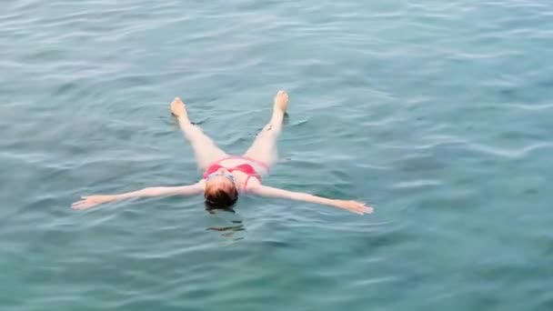 Kvinde i briller ligger en stjerne på havet, tog for at opretholde balancen på vandet, afslapning. Svømmeundervisning. – Stock-video