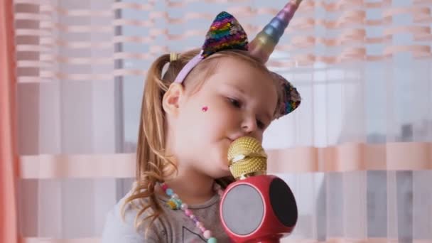 Lustig attraktive verrückte Dame Kind singt in ein Karaoke-Mikrofon, mit einem Einhorn-Stirnband, Kind singt Karaoke-Musik, Spaß haben bei einer Veranstaltung zukünftige Musiker laute Stimme Solo — Stockvideo