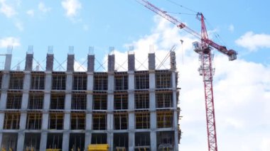 İnşaat vinci ve tamamlanmamış konut binaları mavi gökyüzü ve güneş ışığına karşı. Konut inşaatı, şehirdeki apartman binası, ipotek