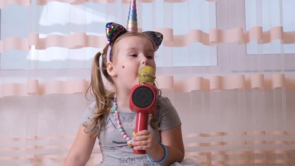 Drôle attrayant fou enfant dame chantant dans un microphone karaoké, avec un bandeau licorne, enfant chantant musique karaoké, amusez-vous lors d'un événement futur musicien voix forte solo — Video