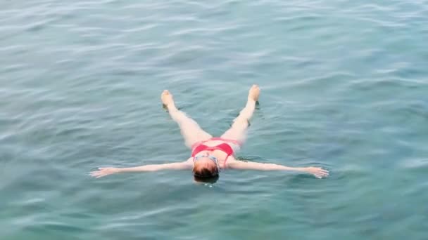 Женщина в очках лежит звезда на море, тренируется для поддержания равновесия на воде, расслабления. Уроки плавания. — стоковое видео