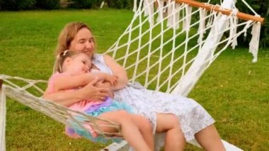 Büyükanne ve torun, 3 yaşında, güneşli bir yaz gününde bahçelerindeki yeşil bir çayırda dinlenip güneşleniyorlar. Tatil konsepti, kuşak ilişkisi, ebeveynlik, mutlu çocukluk..