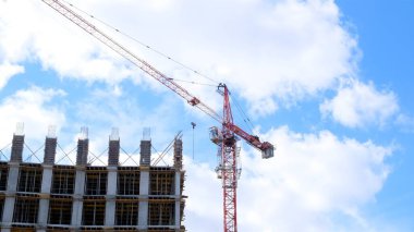 İskeleli bir inşaat alanı, yapım aşamasındaki bir konut binası ve gökyüzünün arka planında bir vinç. Konut inşaatı, şehirdeki apartman binası, ipotek