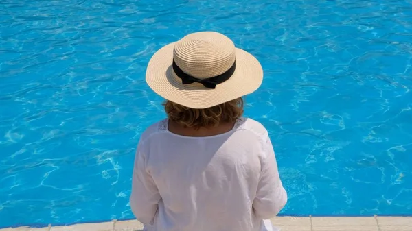 Idős nő pihenés közelében a szállodák kék szabadtéri medence. Az emberek élvezik a nyári vakációt. All inclusive, visszapillantás — Stock Fotó