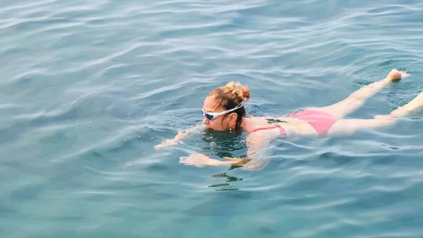 Femelle de 50-55-60 ans, portant des lunettes, des trains pour ramper dans la mer. Nageur professionnel, course de natation. Un nageur rampant devant. Cours de natation. — Photo