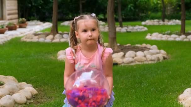 Niña, 3 años de edad, está jugando una pelota inflable transparente con plumas de colores en el interior, con un vestido de arco iris. El concepto de vacaciones de verano, juegos en el hogar, el desarrollo y la educación de — Vídeos de Stock