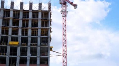 İnşaat vinci ve tamamlanmamış konut binaları mavi gökyüzü ve güneş ışığına karşı. Konut inşaatı, şehirdeki apartman binası, ipotek