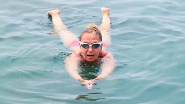 Vrouw in bril en een rood badpak is het beoefenen kruipen zwemmen in de zee. Professionele zwemmer, zwemwedstrijd. Voorste kruipende zwemmer. Zwemlessen. — Stockvideo