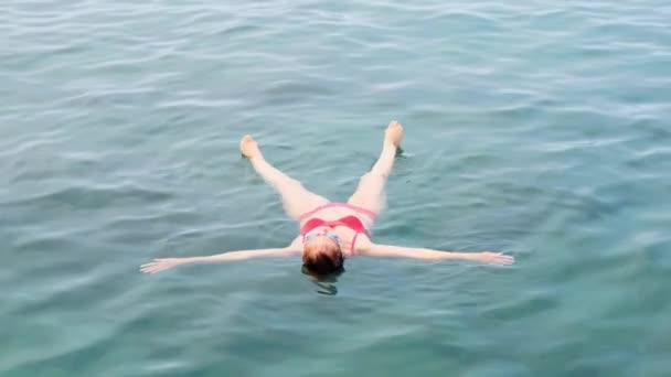 Vrouw in bril ligt een ster op de zee, traint om evenwicht op het water, ontspanning. Zwemlessen. — Stockvideo