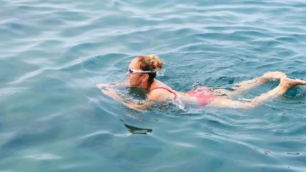 Женщина в возрасте 50-55-60 лет плавает в море ползком. Профессиональный пловец, плавание. Пловец на переднем плане. Уроки плавания. — стоковое фото