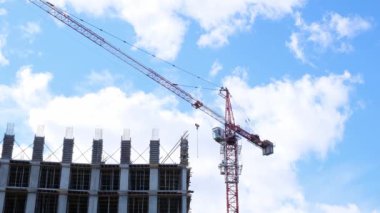 İskeleli bir inşaat alanı, yapım aşamasındaki bir konut binası ve gökyüzünün arka planında bir vinç. Konut inşaatı, şehirdeki apartman binası, ipotek