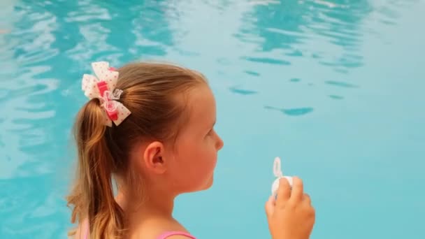 楽しい女の子4-5歳,ポニーテールと,ピンクの水着を着て,夏休みにプールで石鹸ボールを吹いて — ストック動画