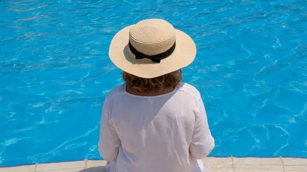Idős nő pihenés közelében a szállodák kék szabadtéri medence. Az emberek élvezik a nyári vakációt. All inclusive, visszapillantás — Stock Fotó