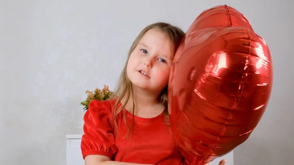 Linda chica sosteniendo globos de grúa en forma de corazón en el día de San Valentín. — Foto de Stock