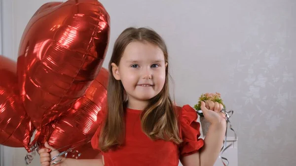 Pretty cute girl holding heart shaped crane balloons on valentines day. — Stockfoto