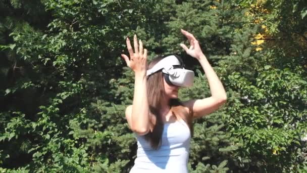 Female wearing virtual reality glasses dances against the background of green trees, representing the fulfillment of a dream. — Stock Video