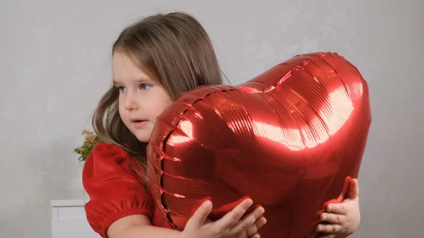 Linda chica sosteniendo globos de grúa en forma de corazón en el día de San Valentín. — Foto de Stock