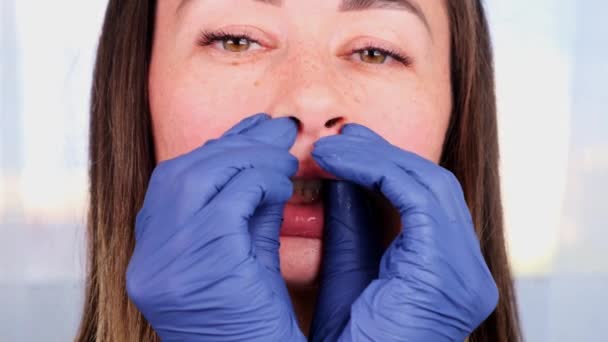 Жінка-лікар косметолог дає букальний масаж обличчя собі, викладаючи і демонструючи внутрішньочерепний нейромедіаційний масаж, крупним планом — стокове відео