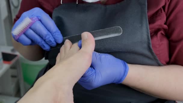 Mistr dělá pedikúru klientovi v salónu krásy, používá pilník na nehty, olupuje kůži nohou. Zavřít, selektivní zaměření. — Stock video