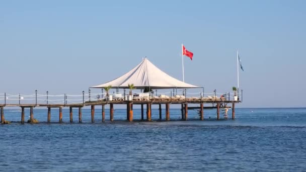 Kleiner Holzsteg am Kieselstrand und Aquamarinwasser im beliebten Touristenort Side am Mittelmeer in der Türkei — Stockvideo