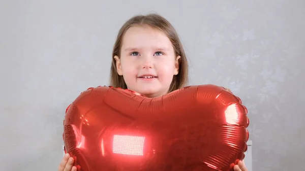 Linda chica sosteniendo globos de grúa en forma de corazón en el día de San Valentín. —  Fotos de Stock