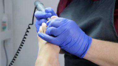 Usta güzellik salonundaki müşterisine ayak ve pedikür için profesyonel bir cihaz kullanarak pedikür yapıyor. Yaklaş, seçici odaklanma.