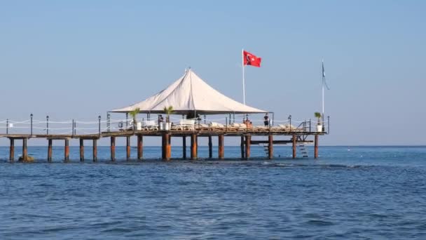 Liten träbrygga på klapperstensstrand och akvamarinvatten i populära turistorten Side vid Medelhavet i Turkiet — Stockvideo