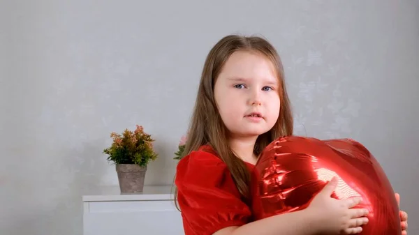 Linda chica sosteniendo globos de grúa en forma de corazón en el día de San Valentín. — Foto de Stock