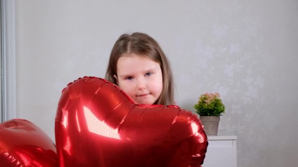 Pretty cute girl holding heart shaped crane balloons on valentines day. — Stock Video