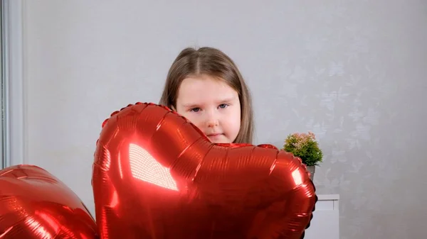 Niña divertida con globos de corazones en día de San Valentín. familia, amor. regalos de vacaciones. felicidad y besos — Foto de Stock